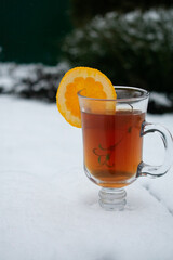 mug with tea and orange in the snow