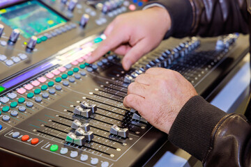 DJ using switch controller mixer to control an audio mixing console live during streaming event