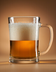 Cold blonde beer in a mug, half full