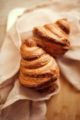 Top view photo of golden brown color, with typical crescent shape and flaky, buttery crust croissants sitting in natural fabric on wooden table. Concept of food, bakery, cuisine, desserts, cooking.