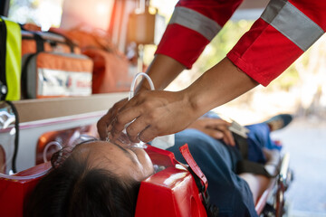 Emergency medical service male nurse rescuer helping a male patient lie on a board performing chest compressions and connecting to a ventilator in an ambulance