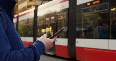 Man waiting tram, engrossed smartphone. Scene depicts urban life, with focus smartphone use. Man tram stop scrolling through smartphone, epitomizing modern connectivity. Conception technologies.