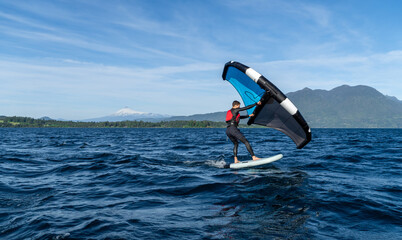Young person learning to wingfoil on the lake with the volcano in the background.
