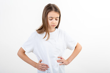 A girl in a white T-shirt on a white background holds her hands on her waist.