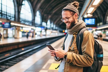 Foto op Aluminium Young smiling man using smartphone on train station © amankris99