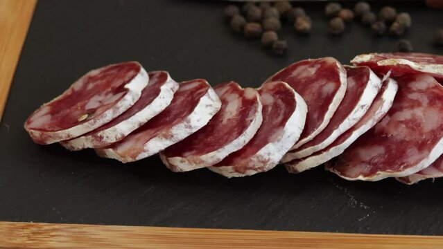 saucisson sec tranch&eacute; sur une planche &agrave; d&eacute;couper