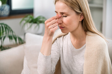woman with headache touching her nose bridge and feeling tired