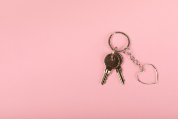 Keychain in the shape of a heart with a key ring on a pink background. Concepts for real estate and moving home or renting property. Buying a property. Mock-up keychain.Copy space.