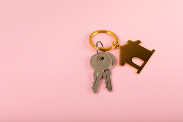 Keychain in the shape of a house with a key ring on a pink background. Concepts for real estate and...