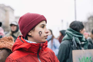 Teenage girl with a woman's symbol painted on her face at a women's day demonstration