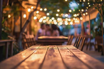 Foto op Plexiglas A romantic outdoor dining setting with a wooden table under a canopy of twinkling lights and a blurred couple in the background © Suplim