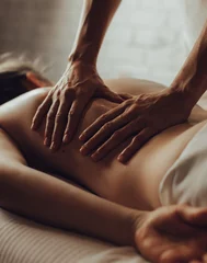 Poster Massagesalon Hands of female chiropractor massaging shoulders of young woman lying on massage table. Concept of physical therapy treatment ,neck pressure point