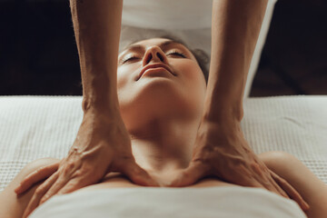 Hands of female chiropractor massaging shoulders of young woman lying on massage table. Concept of physical therapy treatment ,neck pressure point - obrazy, fototapety, plakaty