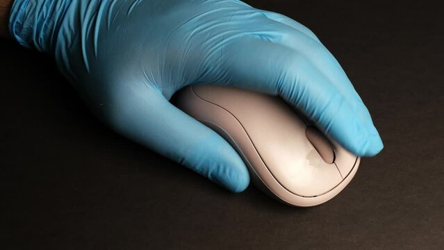 Person in blue gloves using computer mouse