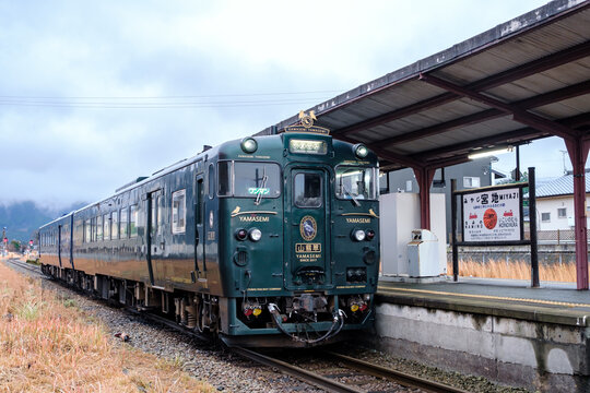 ASO, KUMAMOTO, JAPAN - DEC 16, 2023: JR Kyushu sightseeing train Kawasemi Yamasemi stopping at Miyaji Station. The train is named after the wild birds and features an interior using natural material