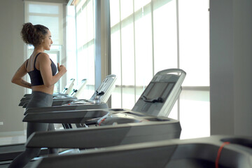 Happy healthy hispanic woman practicing a cardio exercise by running and walking on treadmill...