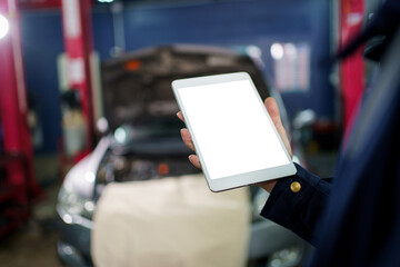 Professional Asian vehicle technician posing for photography in garage. Handsome Asian repairman or technician examining a vehicle in garage.