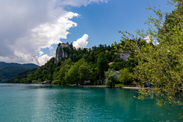Fototapeta na wymiar Panoramic view of St Mary Church of Assumption on the small island and castle at alpine lake Bled, Upper Carniola, Slovenia. Serene landscape in remote untouched nature in the Julian Alps in summer