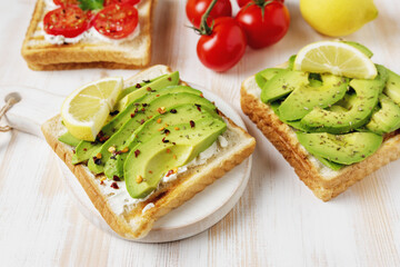 Sliced avocado on toast bread with spices on white wooden background. Food concept.