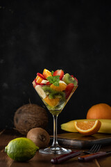 Fruit cocktail in martini glass on wooden table. Food vegan concept.