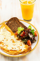 Omelette with cheese, tomatoes, toast and green on white wooden background. Breakfast concept.