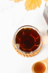 Pure maple syrup in a glass bowl with leaf and wooden spoon on white. Top view. Healthy vegan natural liquid sweetener.