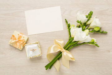 Obraz na płótnie Canvas White fresia flower and gift box with diamond ring on wooden background, top view