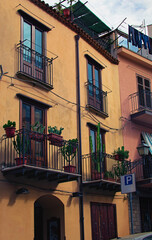 Typical old house with balconies decorated by cacti in flower pots. Traditional view of the building in village Castelbuono. Underwear drying on the balcony fence. Travel and tourism concept