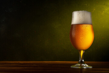 Glass of light beer on a wooden table. Dark background. Drink concept.