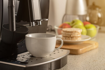 Modern espresso coffee machine with a cup in interior of kitchen closeup.