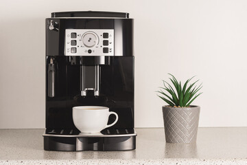 Modern espresso coffee machine with a cup in kitchen.