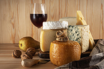 Various kind of cheese with glass of wine on wooden table. Cheese background.