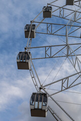 The Ferris wheel attraction is large against the backdrop of a cloudy, textured sky. Vertical photo