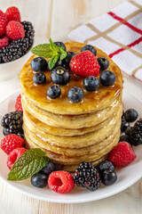 Delicious pancakes with fresh berries on white wooden table. Food concept.