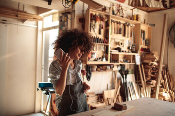 Young woman listening to music in wood workshop