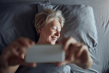 Senior Woman Enjoying Smartphone in Bed