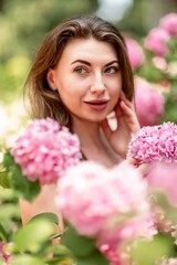 Hydrangeas Happy woman in pink dress amid hydrangeas. Large pink hydrangea caps surround woman. Sunny outdoor setting. Showcasing happy woman amid hydrangea bloom.