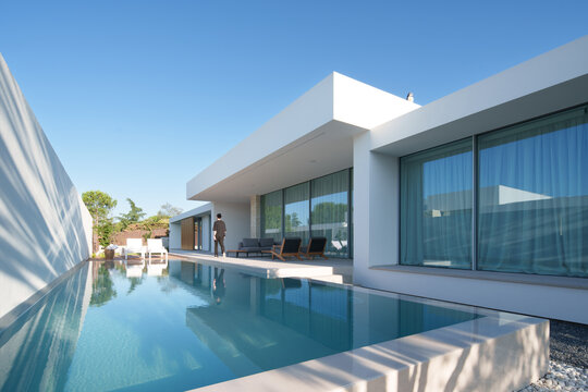 Fototapeta Sleek modern minimalist sustainable house with reflective pool, outdoor seating, and clear skies, emphasizing modern living