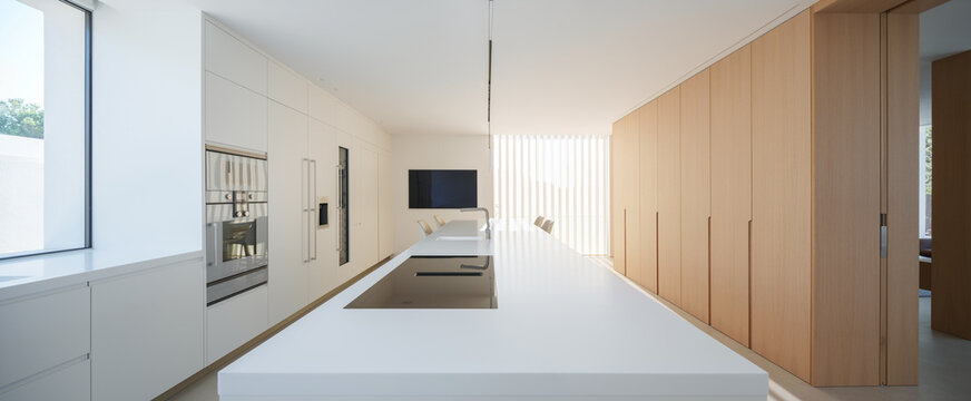 Sleek modern kitchen with clean white lines, integrated appliances, and natural light filtering through slats