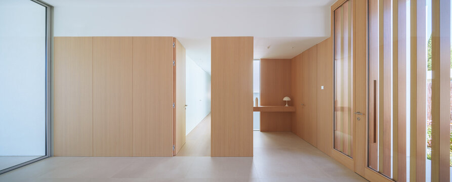 Open plan hallway with wooden partition, stone wall feature, and full-length windows providing garden views