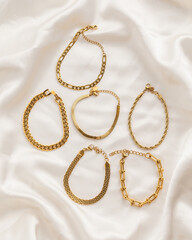 Set of gold chain bracelets on cream silk fabric