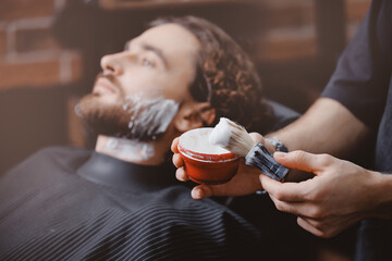 Brush for shaving beard along, blurred background of hair salon for men, barber shop. - obrazy, fototapety, plakaty