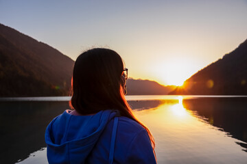 Woman enjoying allure of sunset at alpine lake Weissensee in remote Austrian Alps in Carinthia....