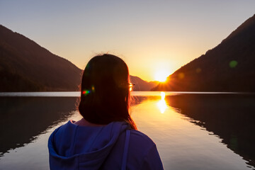 Woman enjoying allure of sunset at alpine lake Weissensee in remote Austrian Alps in Carinthia....