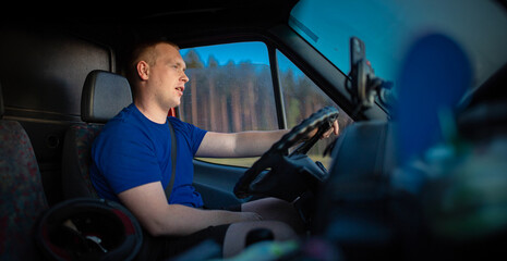 young male truck driver driving a truck during the day. work as a driver
