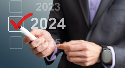 man hand touching on 2024 calender year button on digital virtual screen blur background