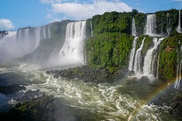 Water cascading over the Iguacu falls with rainbow in Brazil