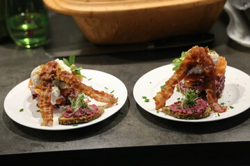 Breakfast arrangement with salmon tartar, poached egg and fried bacon in living room