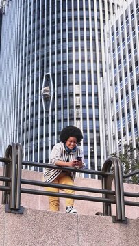 general view of afro woman using tablet leaning on railing, city outdoors, modern background