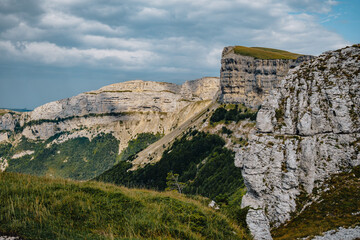 Fototapeta na wymiar View of the alpine meadows of the Font d'Urle plateau in the Vercors (Drôme, France) with its cliffs, limestone rocks, and pastures